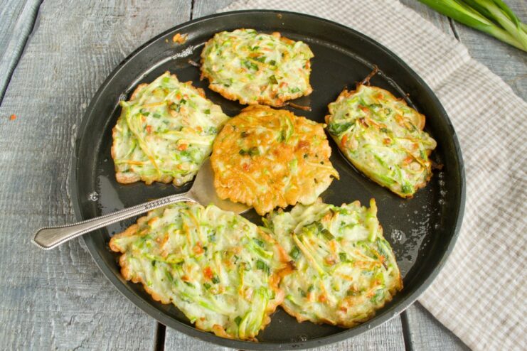 Frying to Perfection: Achieving a Golden-Brown Crust Zucchini fritters frying in a pan, one being flipped to cook the other side.