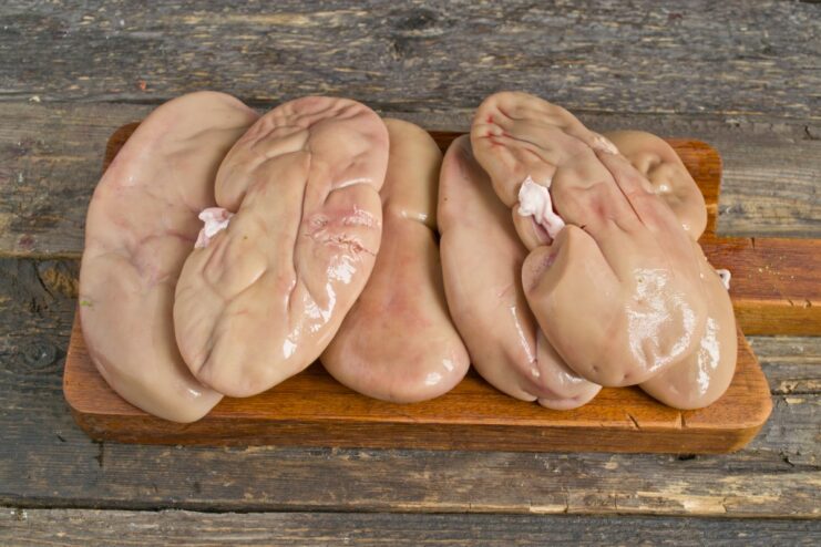 Soaking kidneys is the first step to remove impurities and odor. Raw pork kidneys soaking in a clear bowl of water.