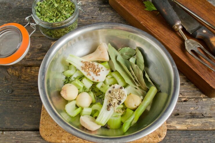 Aromatics like celery, garlic, and spices for the final, flavorful boil. A collection of aromatics: celery, onion, garlic, and spices on a cutting board.