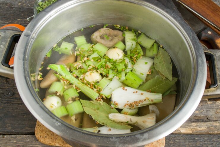 Adding kidneys to seasoned water for the final cooking stage. Parboiled kidneys being added to a pot of boiling water with fresh aromatics.