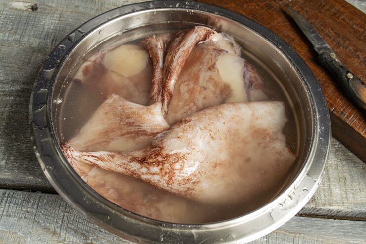 How to properly thaw frozen squid for cooking Frozen squid thawing in a bowl of cold water.