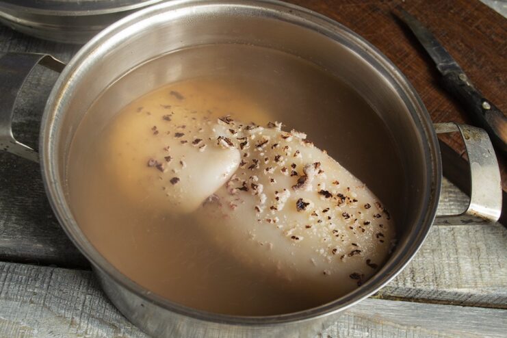 Boiling squid correctly to keep it tender A squid being placed into a pot of boiling water with tongs.