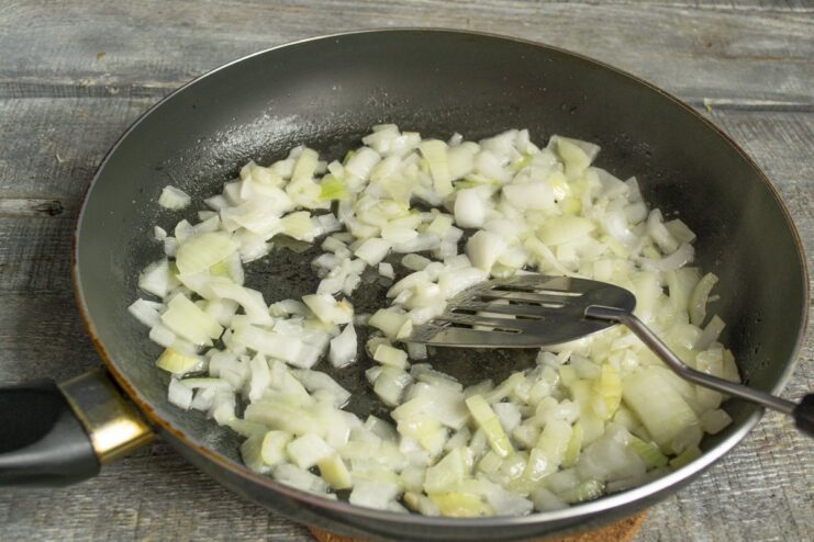 Sautéing aromatics for the tomato sauce base Chopped onion and garlic being sautéed in a pan with butter and oil.