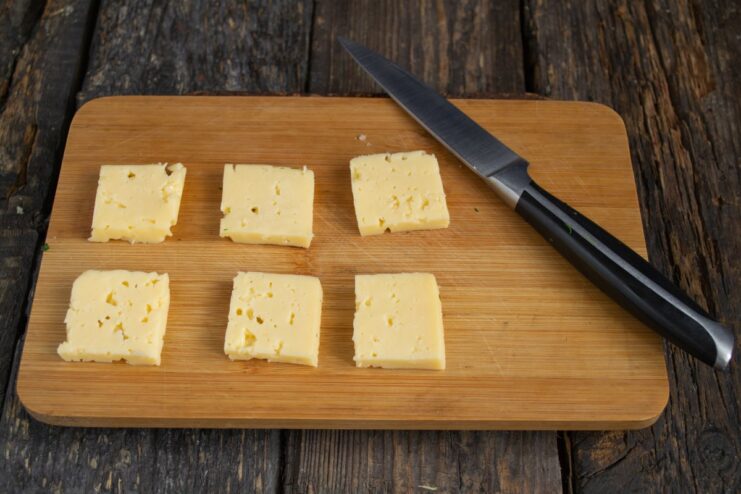 Slicing cream cheese for salmon canapés Slicing a block of creamy cheese into small squares for the canapés.