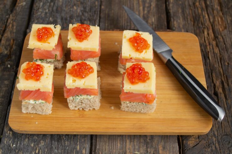 Topping the canapé with red caviar Garnishing the canapé with a small amount of red caviar using a tiny spoon.