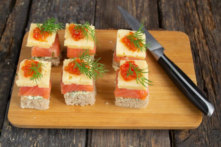 Final touch: garnishing with fresh dill A finished salmon canapé being garnished with a fresh sprig of dill.