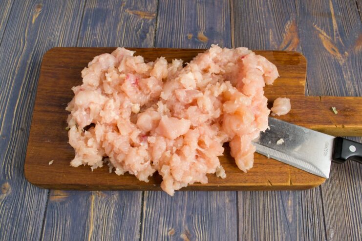 Preparing Ground Chicken from Fillet for the Filling Chicken fillets being processed through a meat grinder to make fresh ground chicken.