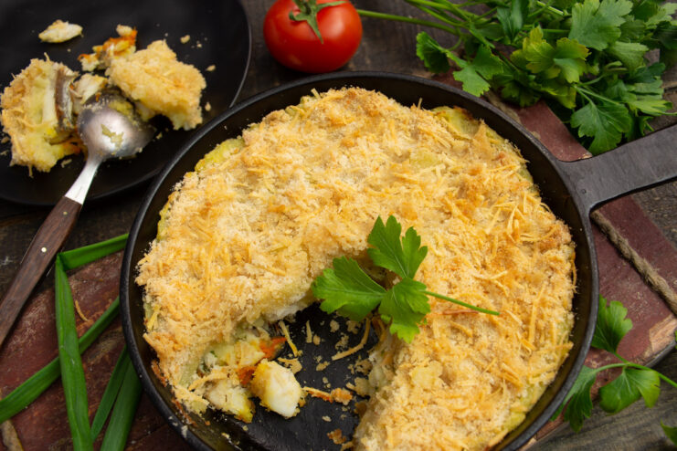 A serving of potato and fish casserole on a plate, showing the creamy potato topping and fish filling.