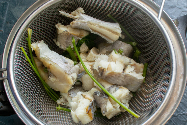 Cooling the cooked fish before deboning Pieces of cooked white fish laid out on a cutting board to cool.
