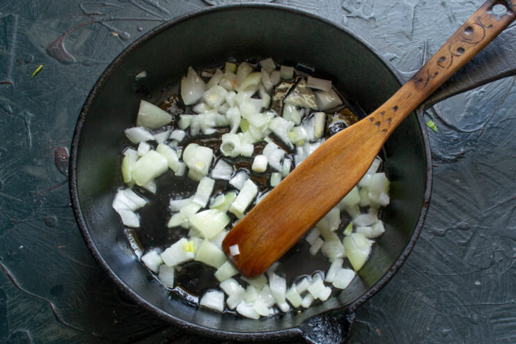 Sautéing chopped onions until soft and translucent Finely chopped onions being sautéed in a skillet with oil.