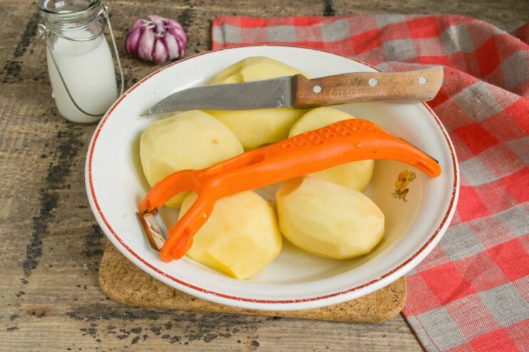 Peeled potatoes soaking in a bowl of cold water to prevent browning.