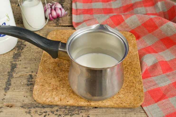 Milk being heated in a small saucepan on the stove.