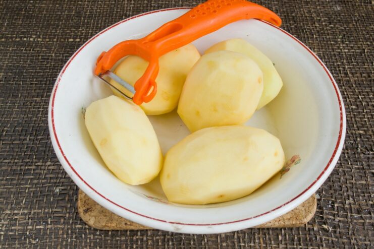 Step 1: Peeling the potatoes for the dumpling dough Peeled raw potatoes in a white bowl of water.