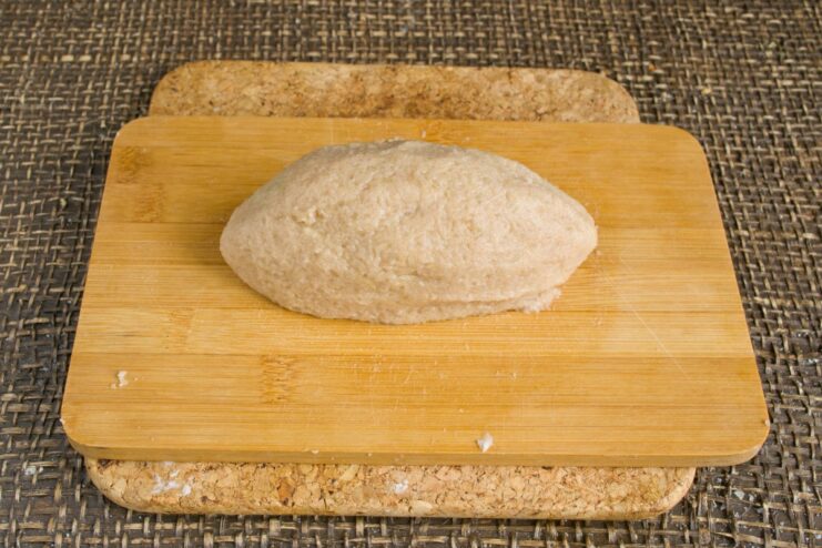 Shaping the meat-filled potato dumplings before cooking Several large, oblong raw potato dumplings filled with meat on a wooden board.