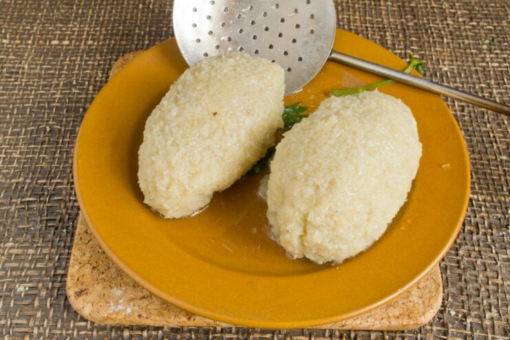 Gently boiling the potato dumplings until cooked through Potato dumplings cooking in a pot of boiling water with herbs.