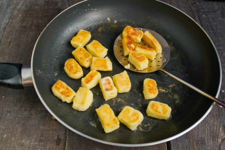 Pan-Frying the Dumplings for a Golden-Brown Crust Švilpikai potato dumplings being pan-fried in a skillet with butter until they are golden brown and crispy.