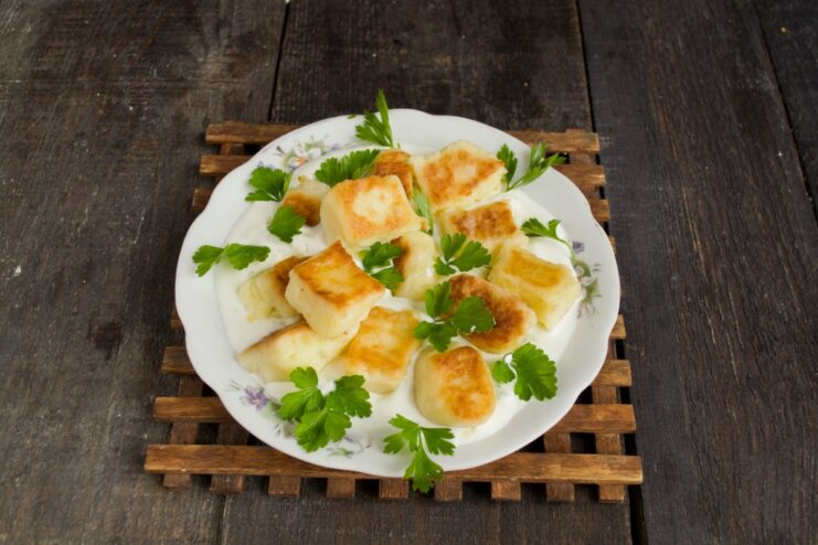 Serving the Švilpikai Hot with Fresh Herbs A finished plate of Švilpikai potato dumplings on a bed of creamy sauce, garnished with fresh dill.