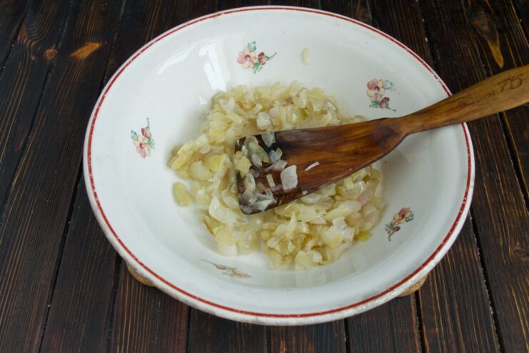 Preparing the Filling: Sautéed Onions A white bowl containing sautéed onions seasoned with black pepper.