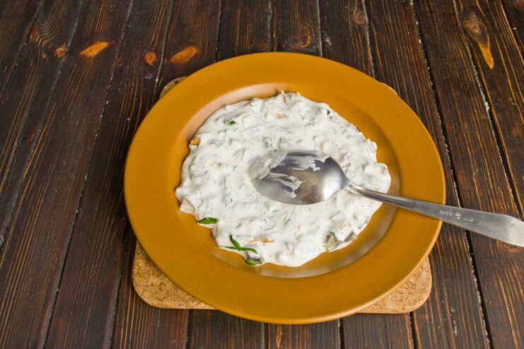 Making the Creamy Smetana and Dill Sauce A bowl of smetana being mixed with chopped dill and green onions to make a sauce.
