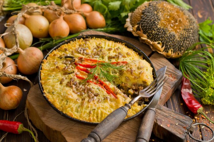 The finished Potato Pie with Minced Meat, ready to be enjoyed. A slice of hot potato pie with minced meat on a plate, garnished with fresh parsley.