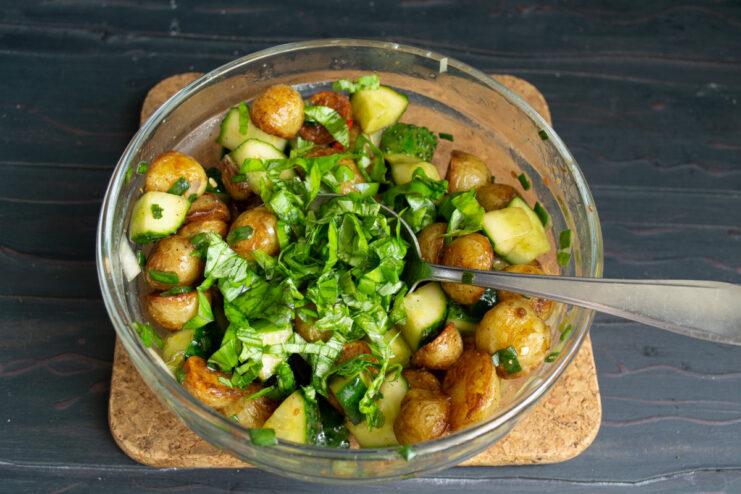 Adding Fresh Basil for Aroma Adding freshly chopped basil leaves to the potato and cucumber salad.