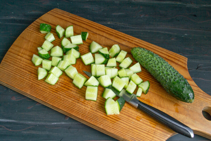 Chopping Fresh Cucumbers for the Salad A pile of freshly chopped cucumbers on a cutting board, ready to be added to the salad.