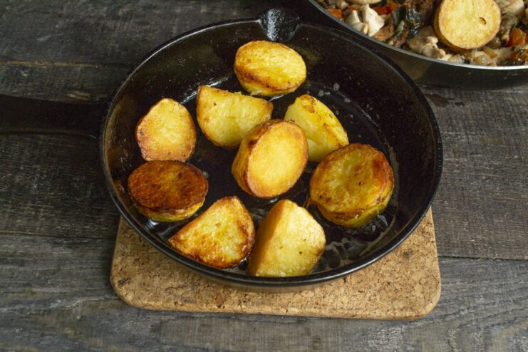 Step 7: Frying the boiled potatoes until golden brown. Boiled new potatoes being fried in a separate pan with butter until golden.
