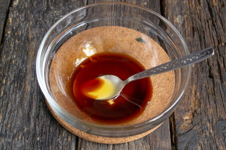 A glass bowl with soy sauce and honey being mixed for the teriyaki sauce.