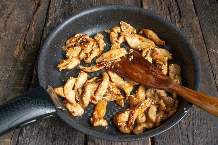 Stirring the teriyaki chicken with sesame seeds in a pan just before serving.