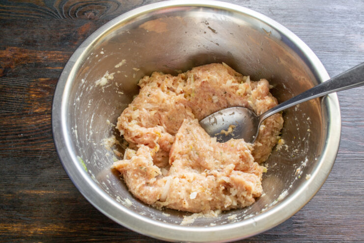Combining All Sausage Ingredients Hands mixing the ground meat, onions, spices, and breadcrumbs in a bowl.