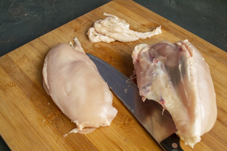 Step 1: Carefully remove the chicken fillet from the breast A hand with a knife cutting a chicken fillet from the breast bone.