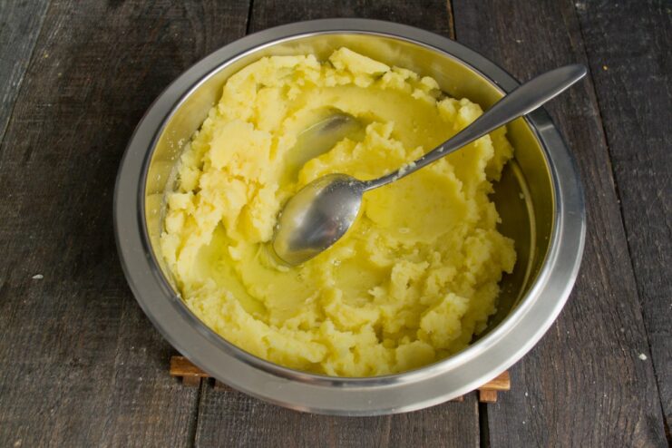 An egg cracked into a bowl of mashed potatoes.