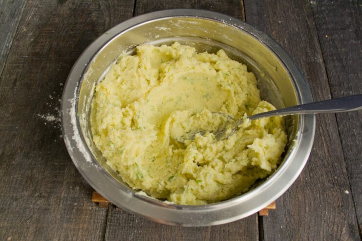 A thick potato dough mixed with dill in a glass bowl.