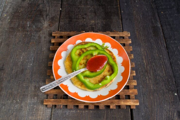 A potato flatbread topped with two bell pepper rings filled with ketchup.