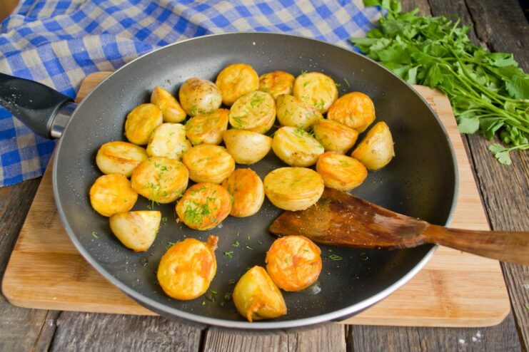 Preparing a Side of Crispy Pan-Fried New Potatoes Boiled new potatoes being pan-fried until golden for a side dish.