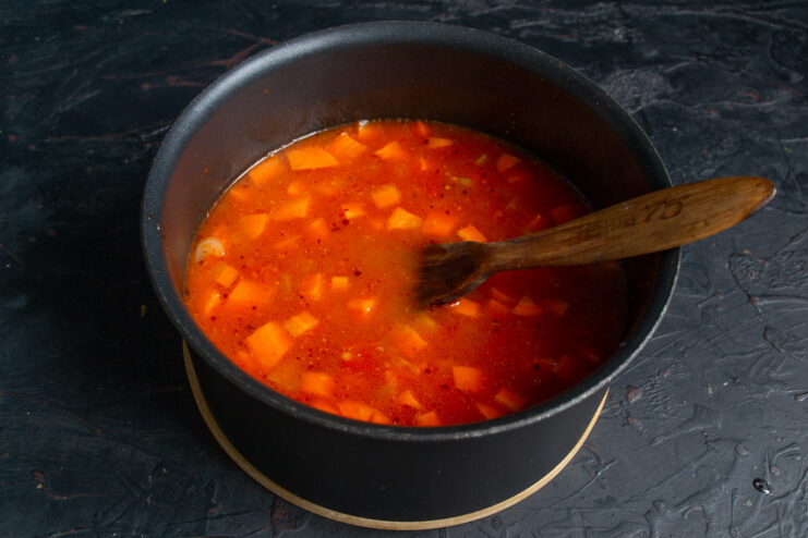 Simmering the soup on low heat with the lid on. A pot of red lentil soup simmering on the stove with the lid on.