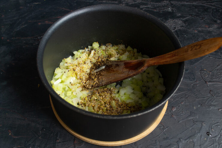 Toasting ground spices with the vegetables to enhance their aroma. A mix of ground spices being added to the sautéed vegetables in the pot.