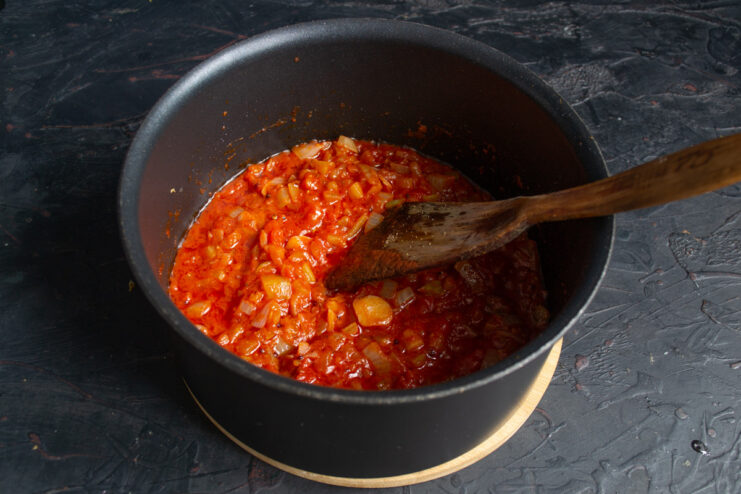 Adding sweet paprika and spicy soybean paste for color and flavor. Sweet paprika and a spoonful of soybean paste being added to the pot.