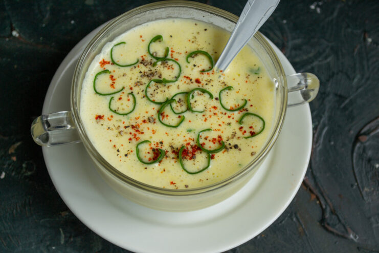 Ready to serve: garnish the creamy soup for extra flavor and color A ladle pouring the finished creamy zucchini soup into a bowl, ready for garnishing.