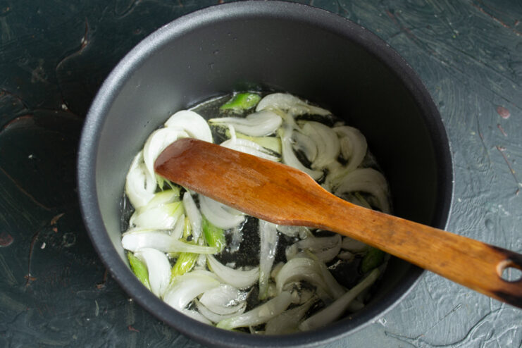 Building the flavor base: sautéing onion and garlic until soft and fragrant Chopped onion and garlic being sautéed in butter in a pot.