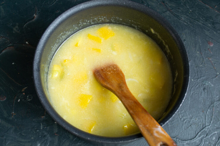Letting the flavors meld: simmer the soup until vegetables are tender A pot of zucchini soup simmering on a stove with a lid on.