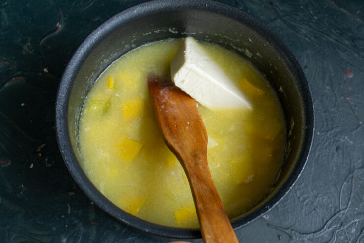 For extra creaminess: stir in processed cheese until it melts completely Cubes of processed cheese being added to the cooked zucchini soup in a pot.