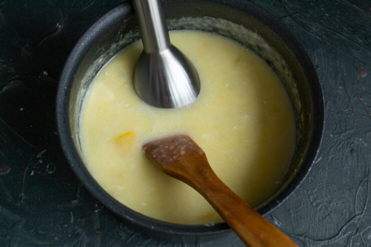 Time to blend: use an immersion blender for a silky-smooth texture An immersion blender is placed in the pot to puree the cooked zucchini soup.