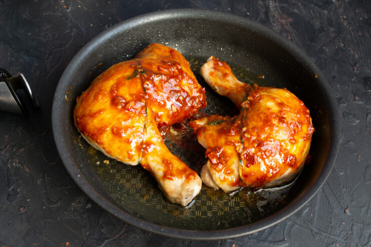 Placing the Glazed Chicken Back into the Oven to Caramelize The skillet with glazed chicken being placed back into the oven.