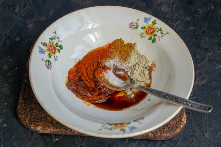 Adding Spices to the BBQ Sauce for a Kick of Heat Spices, including white and red pepper, being added to the BBQ sauce mixture.