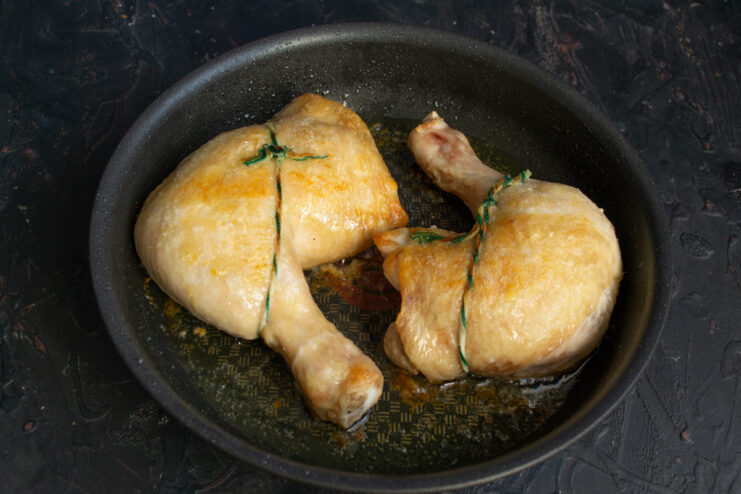 Partially Baked Chicken Ready for its First Layer of Glaze A skillet with partially baked chicken leg quarters taken out of the oven.