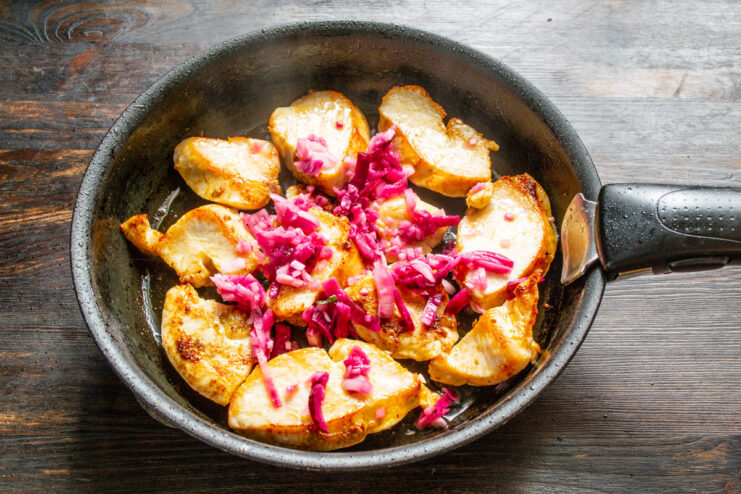 Adding Chopped Onion to the Pan Chopped red onion being added to the frying pan with the chicken.
