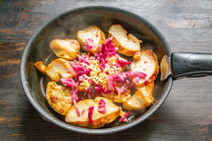 Adding Minced Garlic to the Chicken and Onion Minced garlic being added to the pan with chicken and onions.