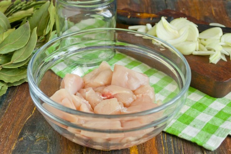 Preparing the Chicken: Cutting Fillet into Chunks Raw chicken fillet being cut into large cubes on a cutting board.