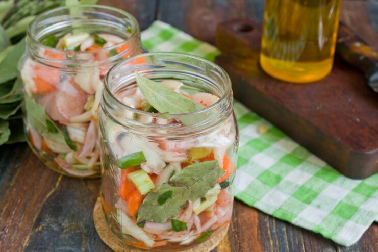 Packing the Jars Tightly for Best Results A hand packing the chicken and vegetable mixture tightly into a glass jar.